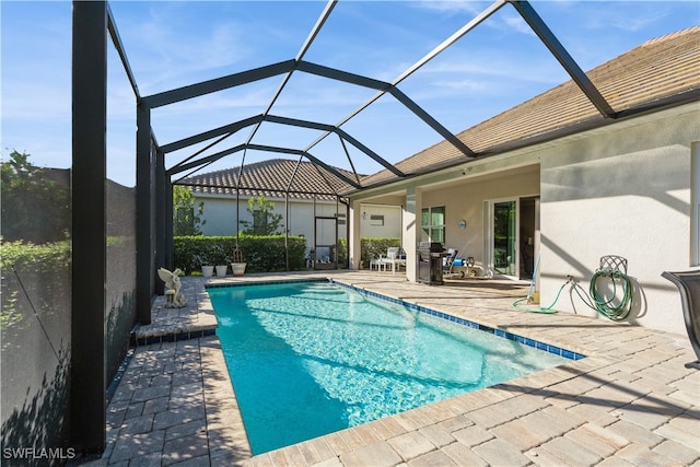 view of pool featuring glass enclosure and a patio