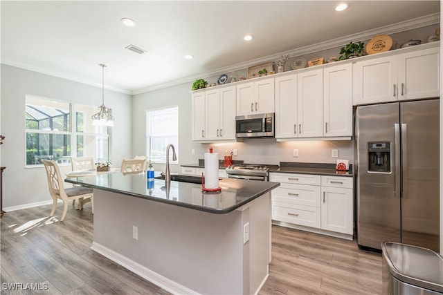 kitchen featuring appliances with stainless steel finishes, light hardwood / wood-style floors, pendant lighting, and sink