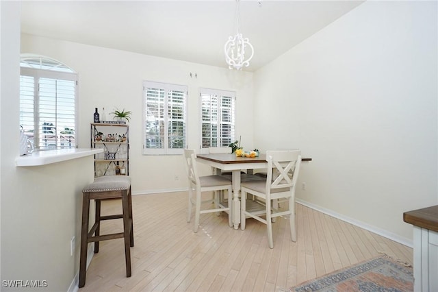 dining area with light hardwood / wood-style floors and a notable chandelier