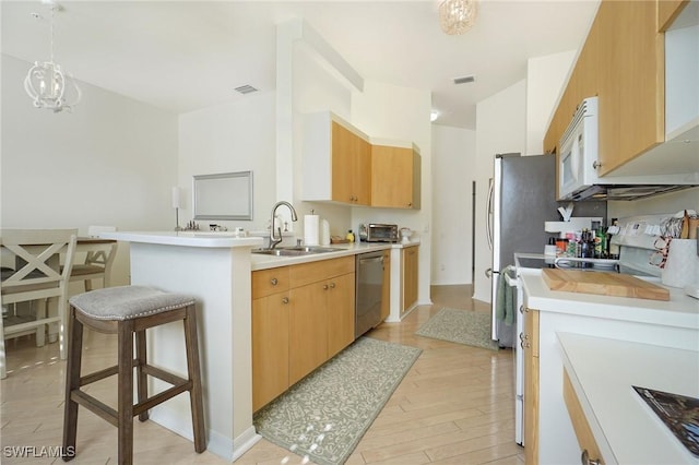 kitchen featuring dishwasher, sink, decorative light fixtures, a kitchen bar, and range