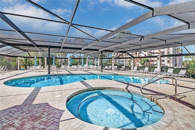 view of swimming pool featuring an in ground hot tub, a patio, and a lanai