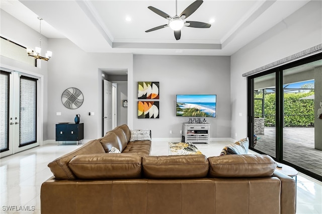 tiled living room with ceiling fan with notable chandelier, a raised ceiling, and french doors