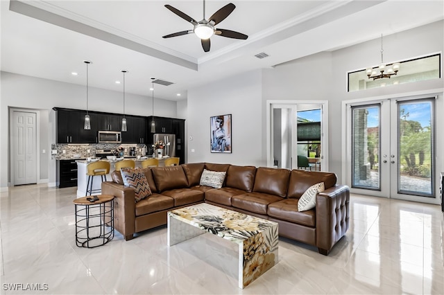 living room with ceiling fan with notable chandelier, crown molding, a tray ceiling, and french doors