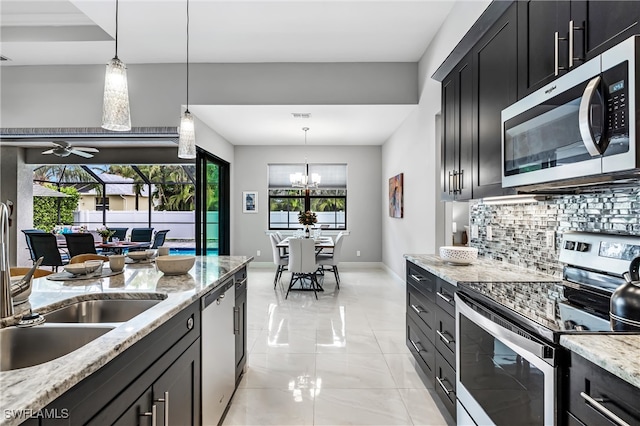 kitchen featuring a wealth of natural light, light stone countertops, decorative light fixtures, and appliances with stainless steel finishes