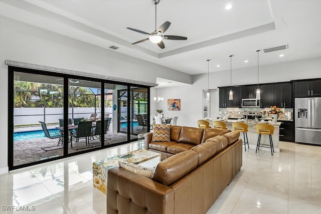 living room with a tray ceiling and ceiling fan