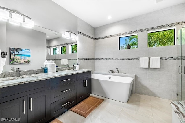 bathroom with vanity, a healthy amount of sunlight, tile walls, and independent shower and bath