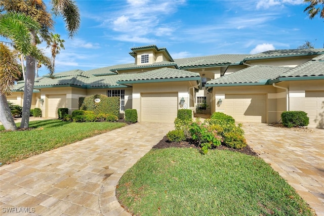 mediterranean / spanish-style home featuring a garage and a front lawn