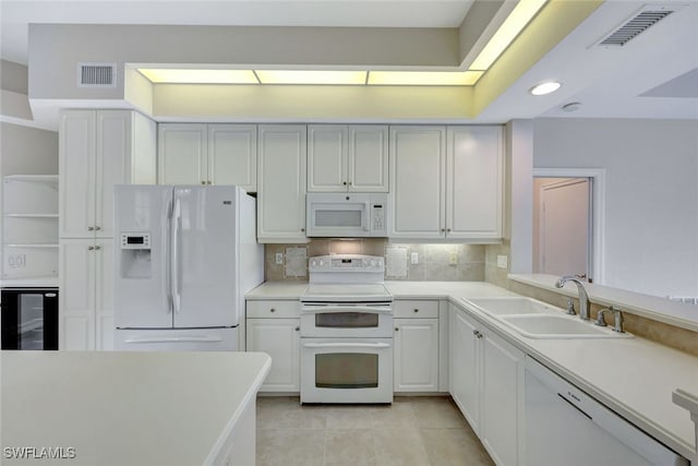 kitchen with decorative backsplash, white appliances, beverage cooler, sink, and white cabinetry