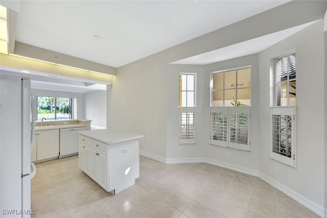 kitchen featuring white cabinetry, sink, light tile patterned floors, white appliances, and a kitchen island