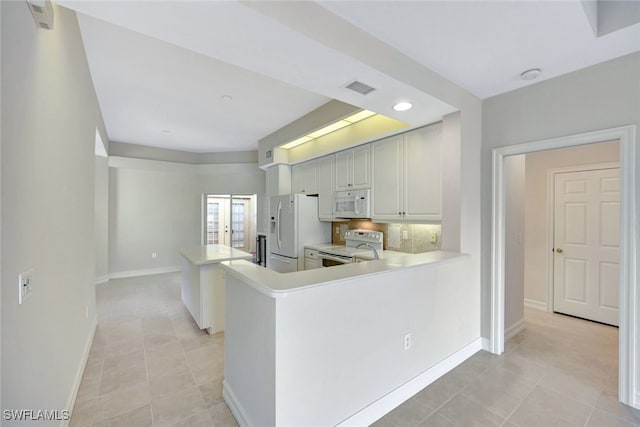 kitchen with kitchen peninsula, light tile patterned floors, white cabinets, and white appliances