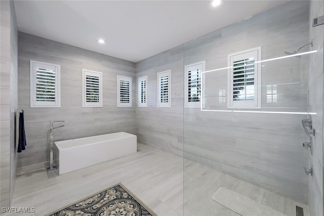 bathroom featuring plus walk in shower and tile walls