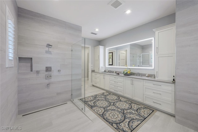 bathroom featuring vanity, a shower with shower door, and tile walls