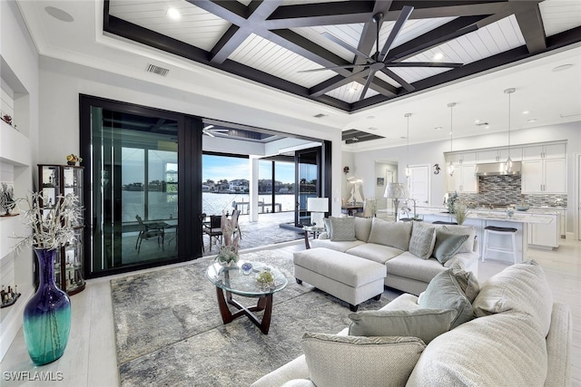 living room with ceiling fan, coffered ceiling, beamed ceiling, light hardwood / wood-style floors, and ornamental molding