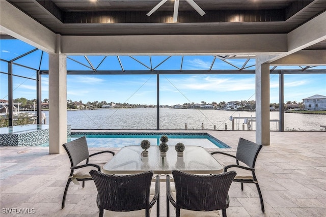 view of patio with a lanai, ceiling fan, and a water view