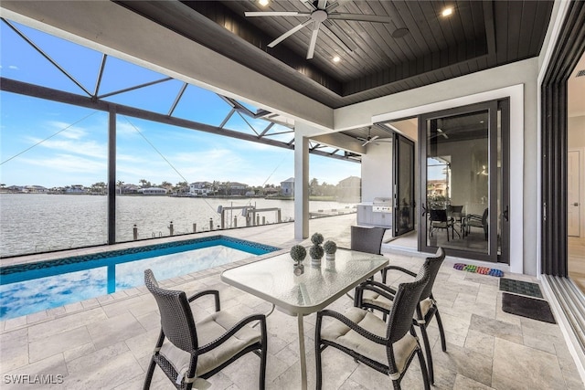 view of patio featuring a water view, ceiling fan, and a lanai