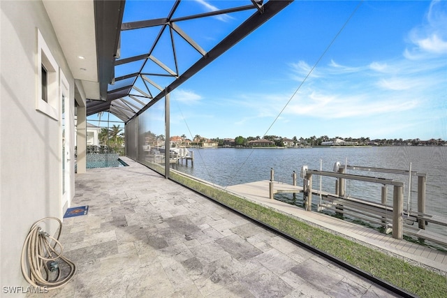 view of dock featuring glass enclosure, a water view, and a patio