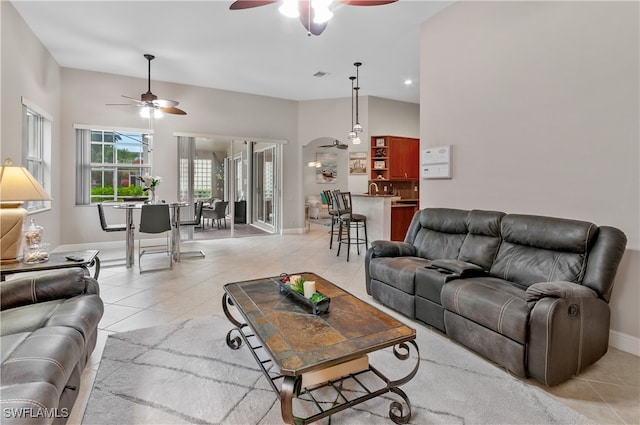 tiled living room with ceiling fan and a towering ceiling