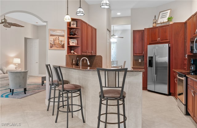 kitchen with a kitchen breakfast bar, hanging light fixtures, ceiling fan, kitchen peninsula, and stainless steel appliances