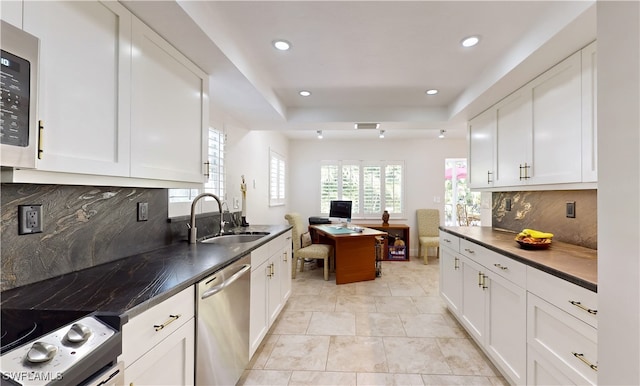 kitchen with tasteful backsplash, sink, white cabinets, and stainless steel appliances