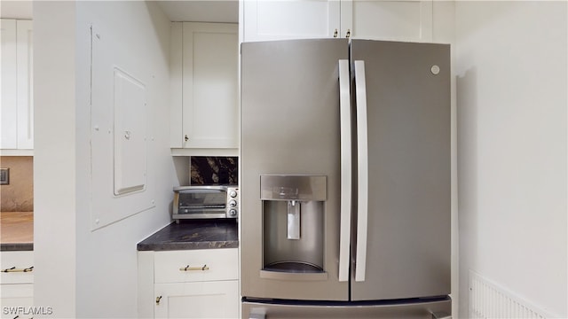 kitchen featuring stainless steel fridge and white cabinetry