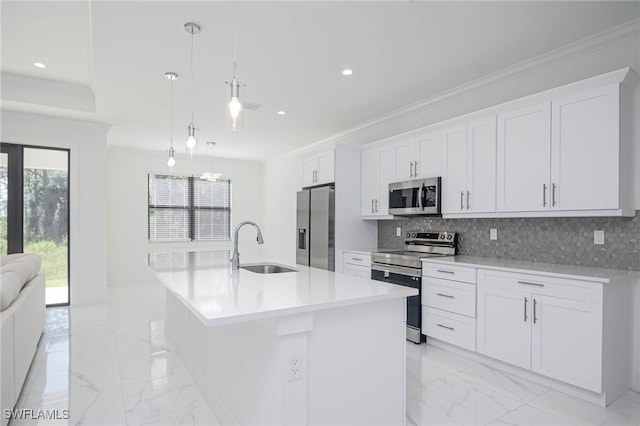 kitchen with white cabinets, appliances with stainless steel finishes, decorative light fixtures, and a kitchen island with sink