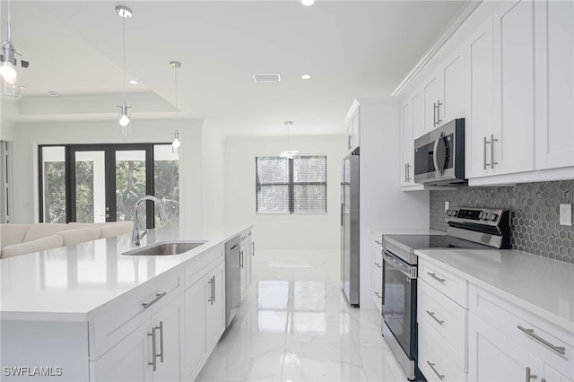 kitchen with pendant lighting, sink, an island with sink, appliances with stainless steel finishes, and white cabinetry