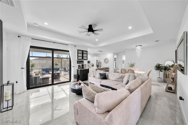 living room with ceiling fan and a raised ceiling