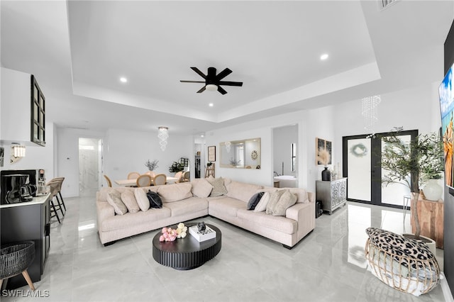 living room featuring a raised ceiling and ceiling fan