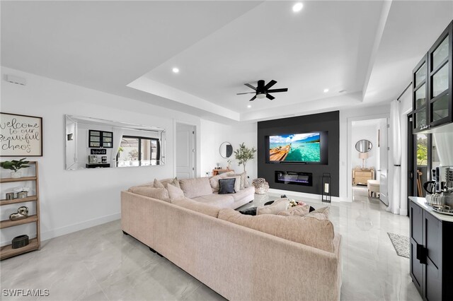 living room with a tray ceiling and ceiling fan