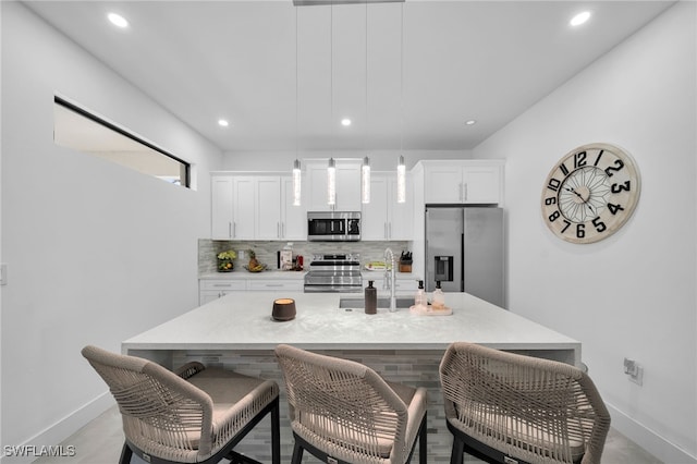 kitchen featuring appliances with stainless steel finishes, tasteful backsplash, a kitchen island with sink, sink, and white cabinetry