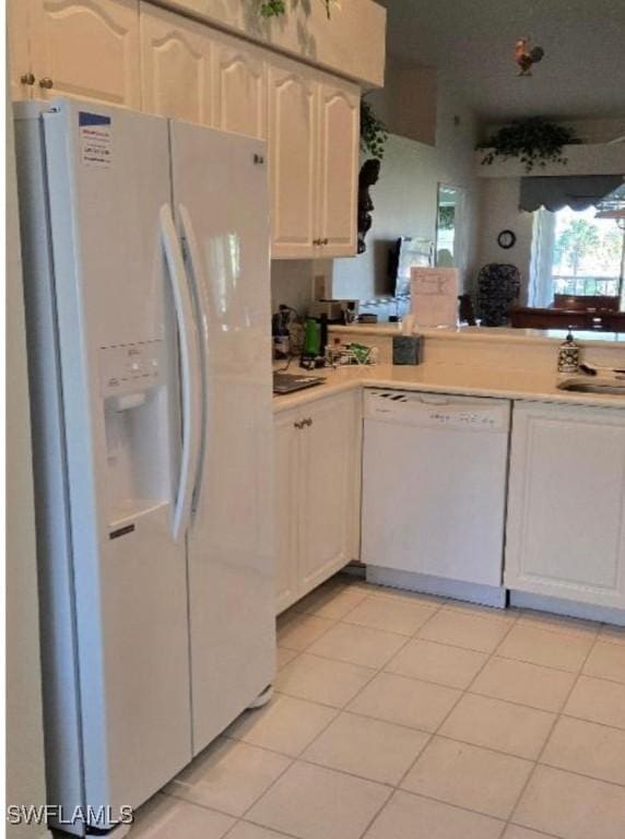 kitchen with white appliances, sink, light tile patterned floors, and white cabinetry