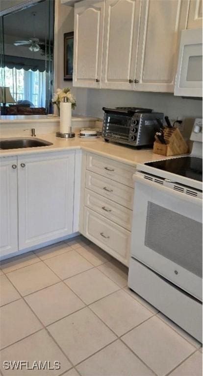 kitchen with white appliances, white cabinetry, sink, and light tile patterned floors