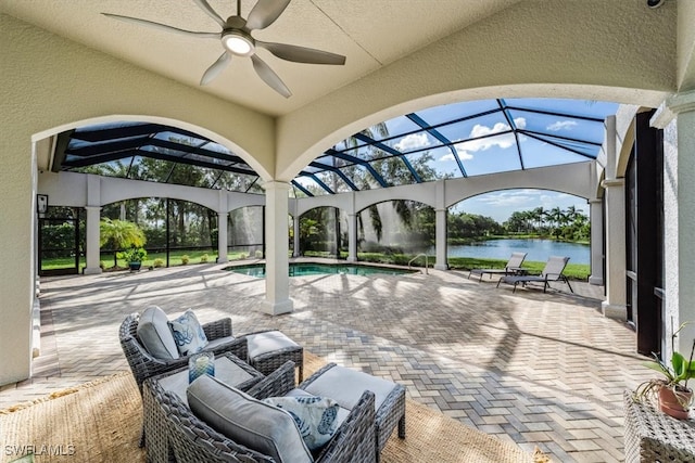 view of patio / terrace featuring a lanai, ceiling fan, a water view, and outdoor lounge area