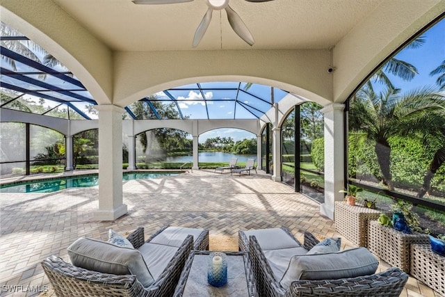 view of patio with a water view, ceiling fan, and a lanai