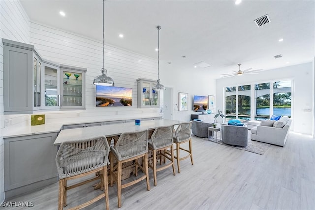 kitchen featuring kitchen peninsula, a kitchen breakfast bar, ceiling fan, decorative light fixtures, and gray cabinets