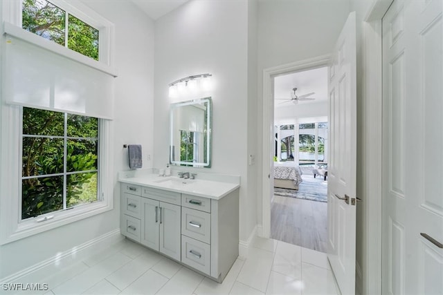 bathroom with ceiling fan, a towering ceiling, vanity, and a healthy amount of sunlight