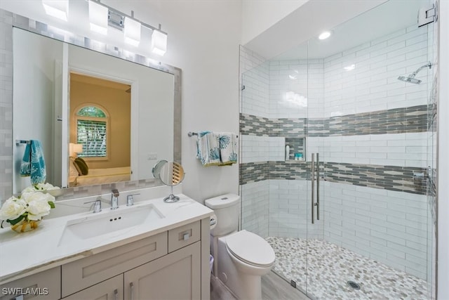 bathroom featuring hardwood / wood-style flooring, vanity, toilet, and a shower with shower door