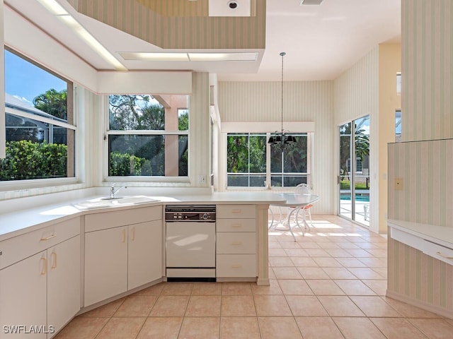 kitchen with white dishwasher, light tile patterned flooring, white cabinetry, and hanging light fixtures