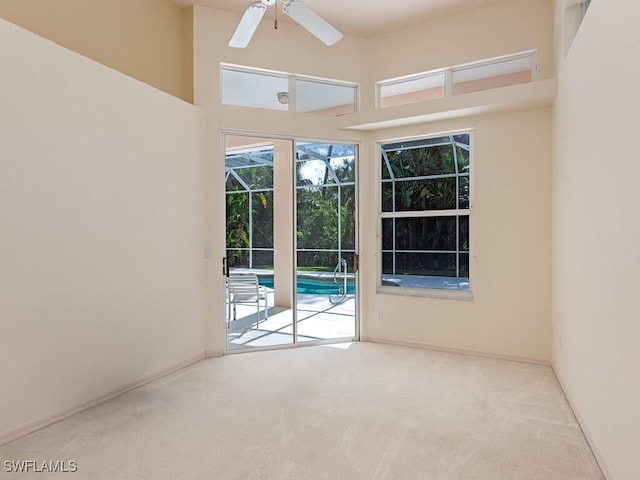 carpeted empty room with a high ceiling and ceiling fan