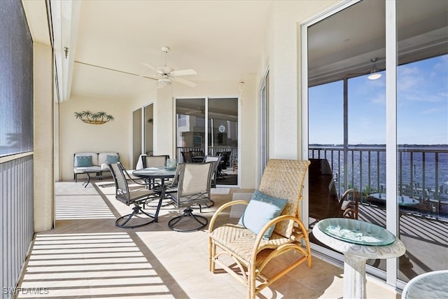 sunroom featuring ceiling fan and a water view