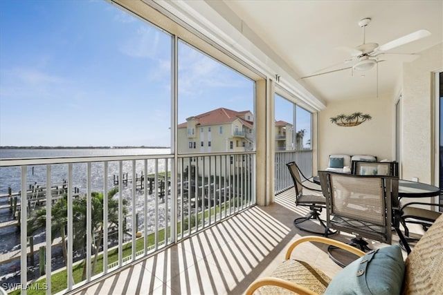 sunroom featuring ceiling fan and a water view