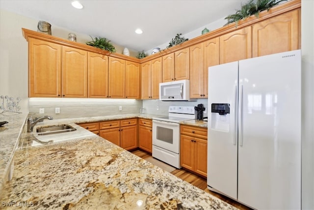 kitchen with backsplash, white appliances, sink, light brown cabinets, and light hardwood / wood-style flooring