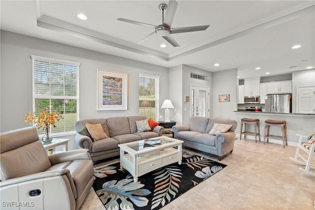 living room with ornamental molding, a healthy amount of sunlight, and a raised ceiling