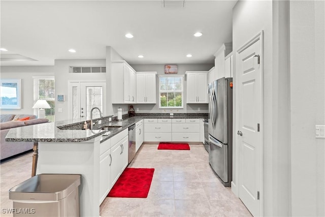 kitchen with white cabinetry, stainless steel appliances, kitchen peninsula, and sink