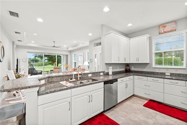 kitchen featuring sink, white cabinetry, a raised ceiling, stainless steel dishwasher, and kitchen peninsula