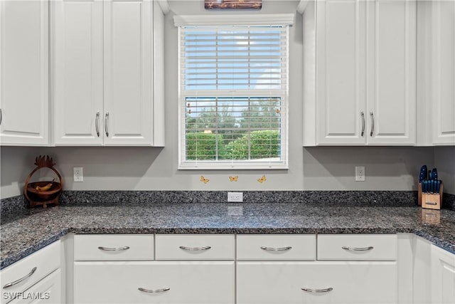 kitchen featuring white cabinetry and dark stone countertops