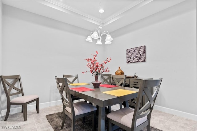 tiled dining room with ornamental molding, a tray ceiling, and a chandelier