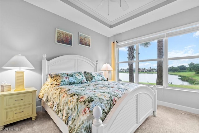 carpeted bedroom with multiple windows, a tray ceiling, ornamental molding, and a water view