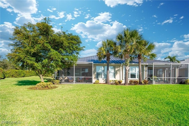 back of property featuring a lanai and a lawn