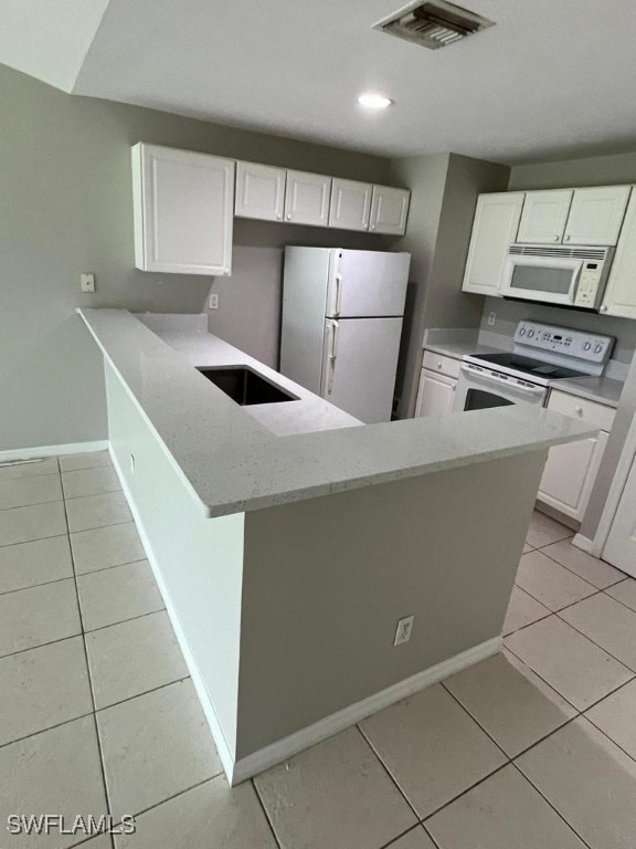 kitchen with kitchen peninsula, white appliances, sink, light tile patterned floors, and white cabinets